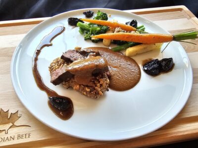 Cooks the Books: Grilled Denver Steak “Bakareta” with tomato liver sauce, California Walnut crusted rice cake and glazed California Prunes.